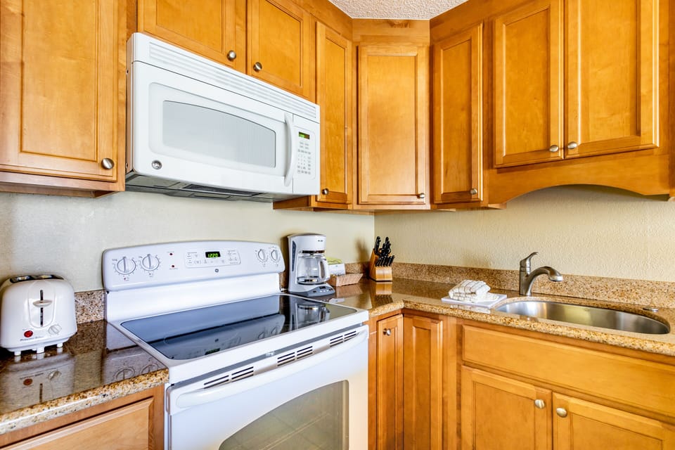 Your fully equipped kitchen features warm wood cabinetry, granite counters, and everything you need to prepare meals during your stay, including a microwave, stove, and coffee maker.