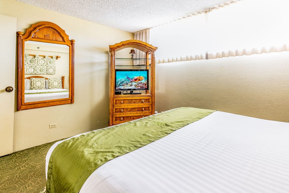 Sink into crisp white linens adorned with a soft green runner, your private retreat featuring warm wood accents and calming decor that invites restful nights.