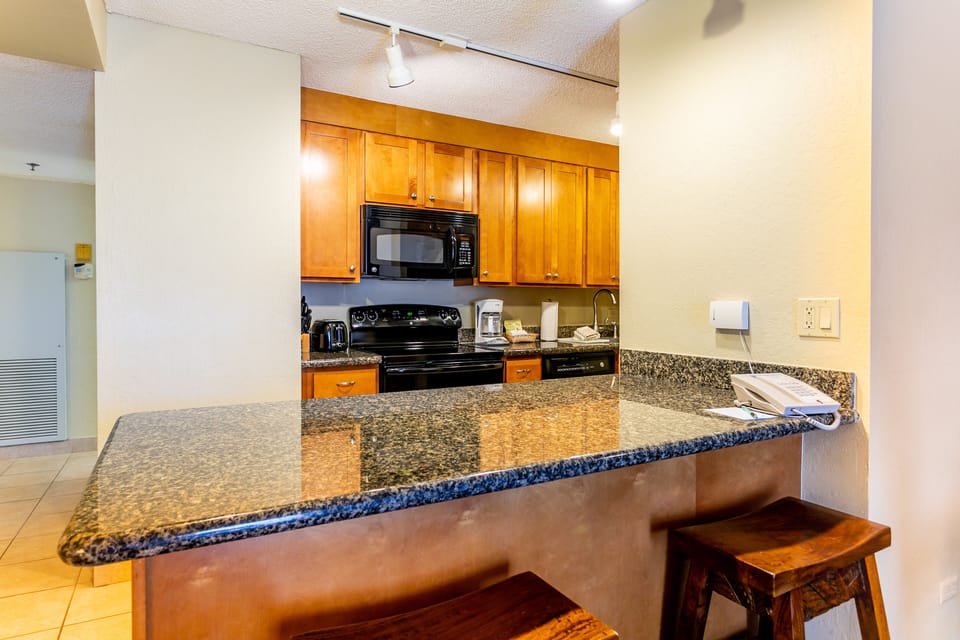 A fully-equipped kitchen with granite counters, warm wood cabinetry, and modern appliances awaits your culinary adventures during your stay.