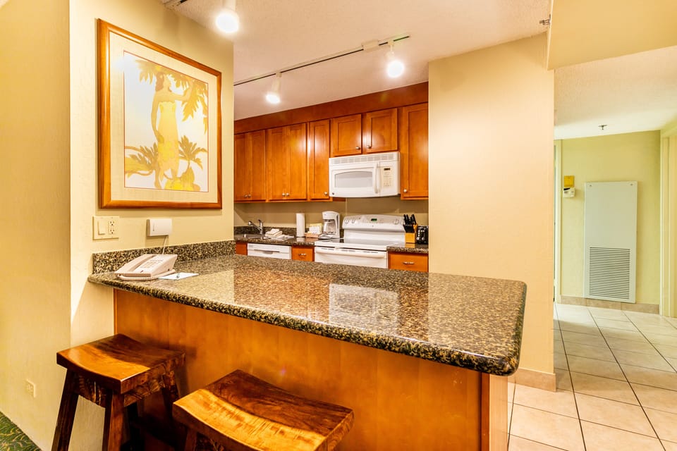 Picture yourself preparing meals in this well-appointed kitchen with granite counters, rich wood cabinetry, and modern appliances—perfect for enjoying your favorite recipes on vacation.
