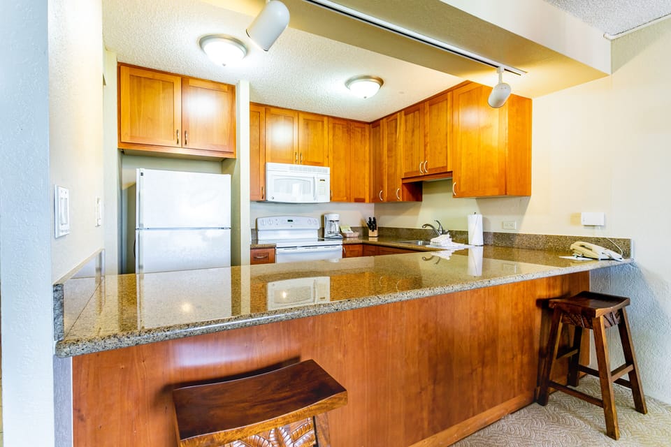 Your fully equipped kitchen features warm wood cabinetry, granite countertops, and modern appliances—perfect for preparing home-cooked meals during your stay.