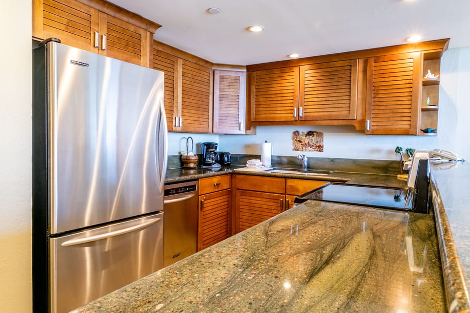 Your fully equipped gourmet kitchen awaits, featuring granite countertops, sleek stainless steel appliances, and warm cabinetry—perfect for preparing meals or enjoying morning coffee in style.