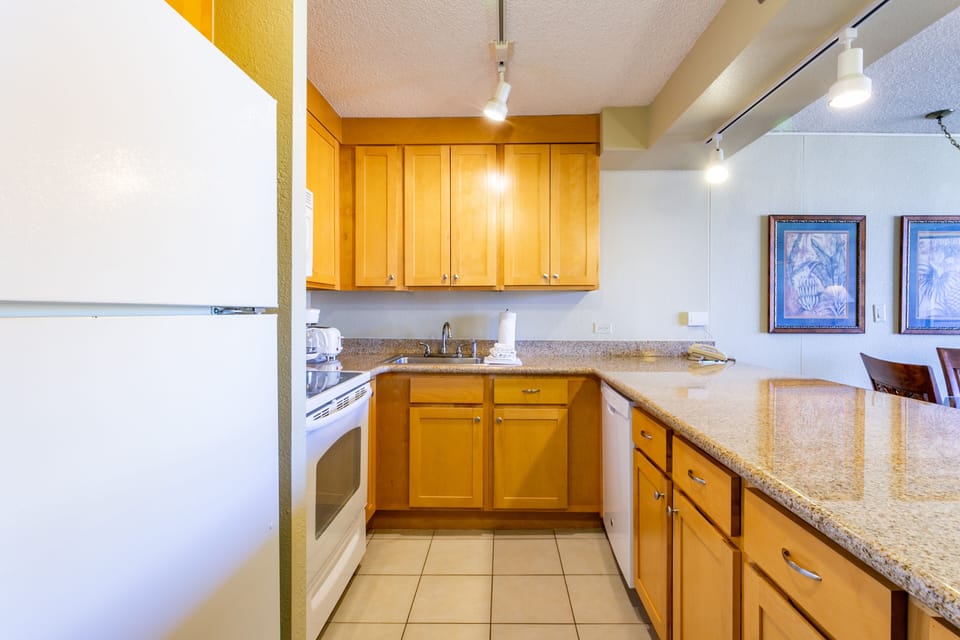Your fully equipped kitchen features granite countertops, modern appliances, and warm wood cabinetry—perfect for preparing meals during your stay.