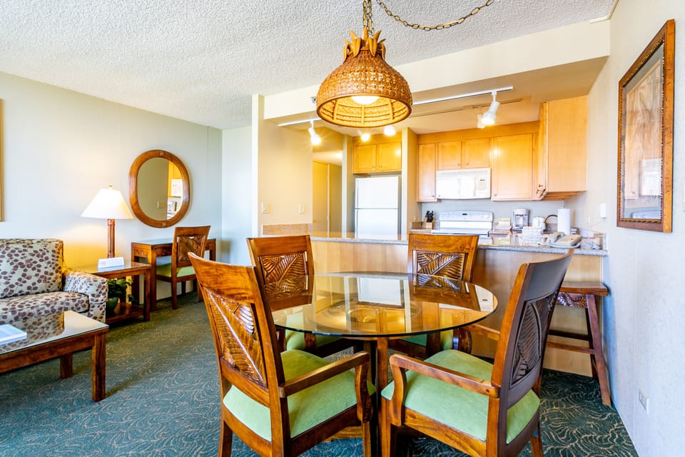 Relax in your island-inspired space with a welcoming living area flowing into a fully-equipped kitchen. The warm pendant lighting and tropical-carved dining chairs invite you to gather, cook, and unwind in effortless comfort.