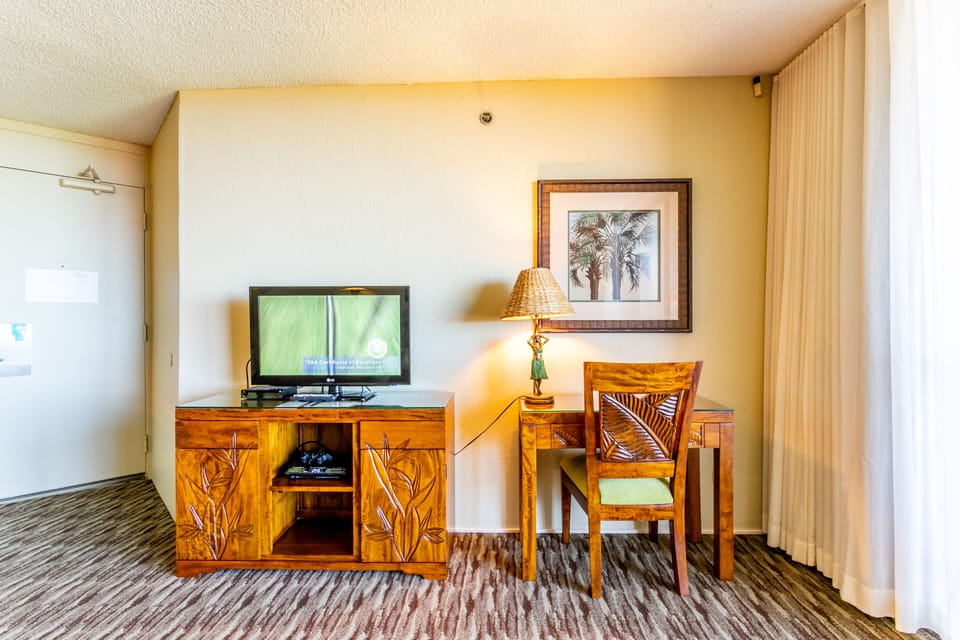 Your tropical-inspired retreat features a cozy desk and entertainment center, perfect for unwinding after beach days or catching up on work with island charm surrounding you.
