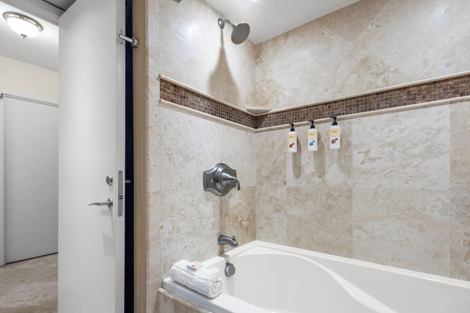 Step into your private oasis with a sleek tub-shower combo, rainfall showerhead, and designer tile with mosaic accents—perfect for unwinding after a day of adventure.