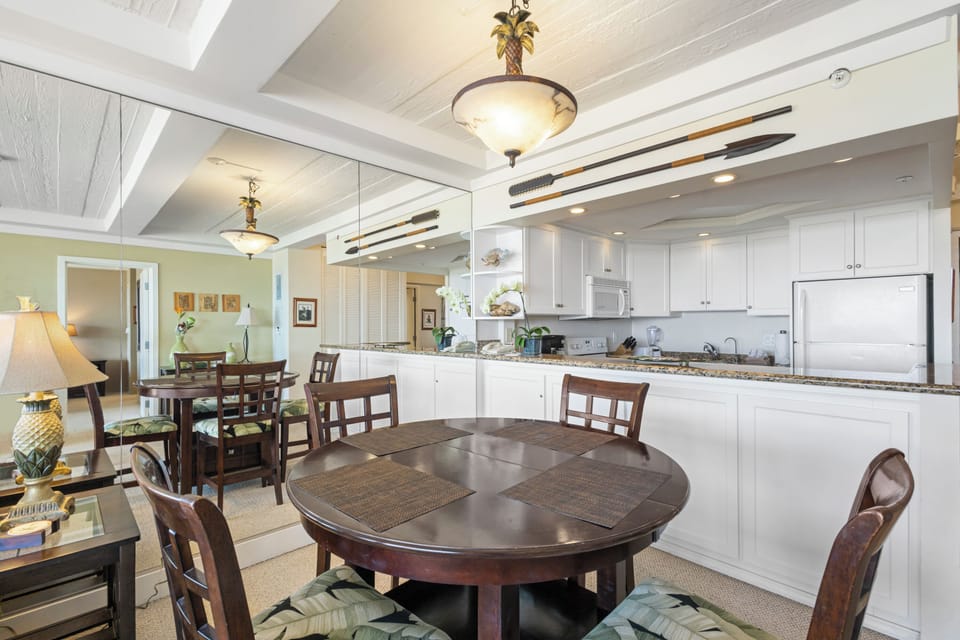 Your open-concept kitchen and dining area invites you to gather and create memories, with sleek white cabinetry, modern appliances, and warm wood dining tables ready for your meals together.