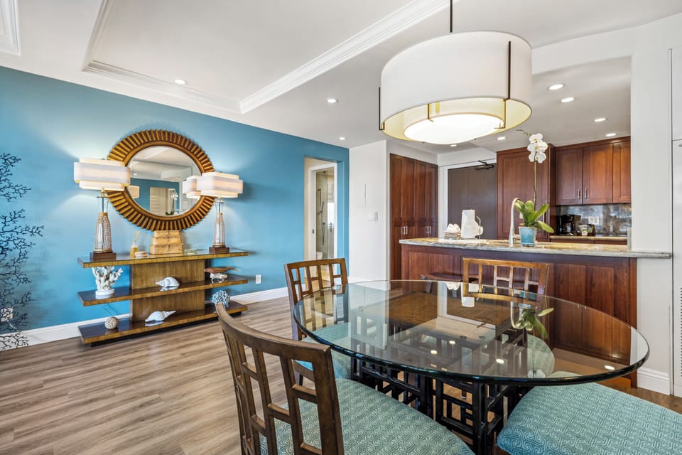 Your open dining and kitchen area blends elegance with comfort, featuring warm wood tones, modern lighting, and a stylish blue accent wall that creates an inviting atmosphere.