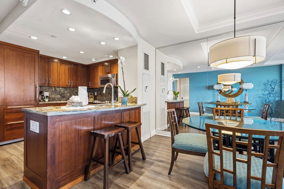 Step into this beautifully appointed kitchen and dining space, where warm wood cabinetry meets serene blue accents. The spacious island invites morning coffee, while the elegant dining area awaits shared meals and laughter.