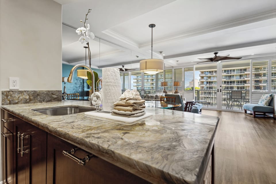 Your kitchen flows seamlessly into an inviting living space with elegant marble countertops, stylish lighting, and balcony access framing stunning views beyond.