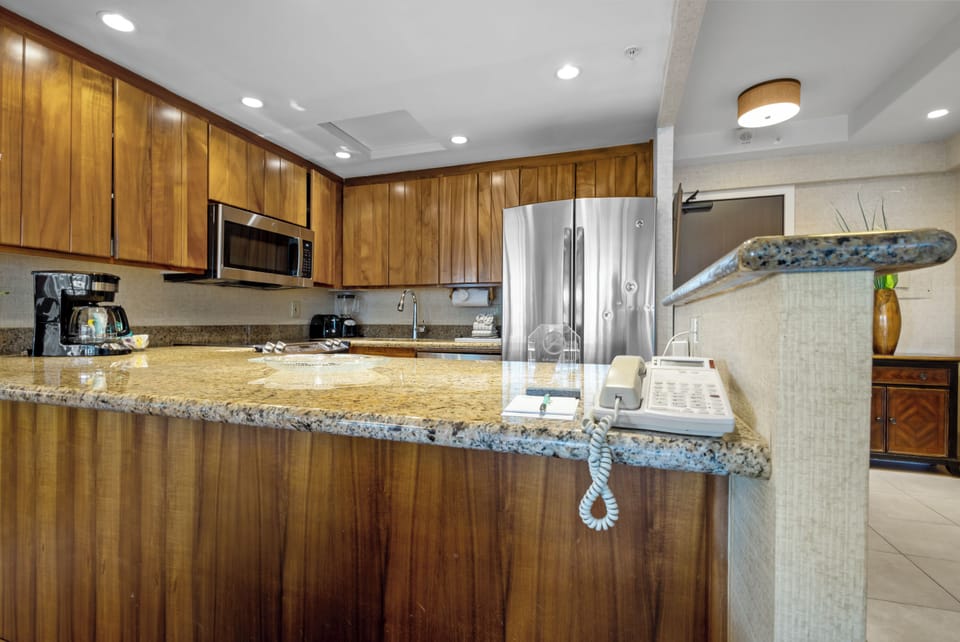 Your fully equipped kitchen awaits with gleaming granite countertops, rich wood cabinetry, and modern appliances—perfect for preparing your favorite meals or brewing morning coffee in comfort.