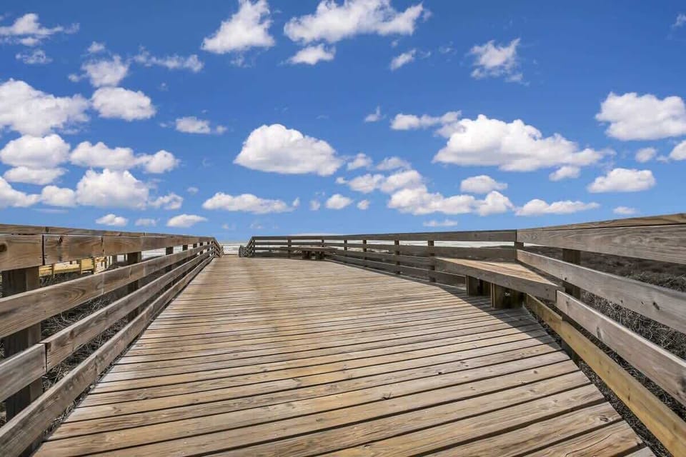 Boardwalk cutting through dunes, leading straight toward the beach