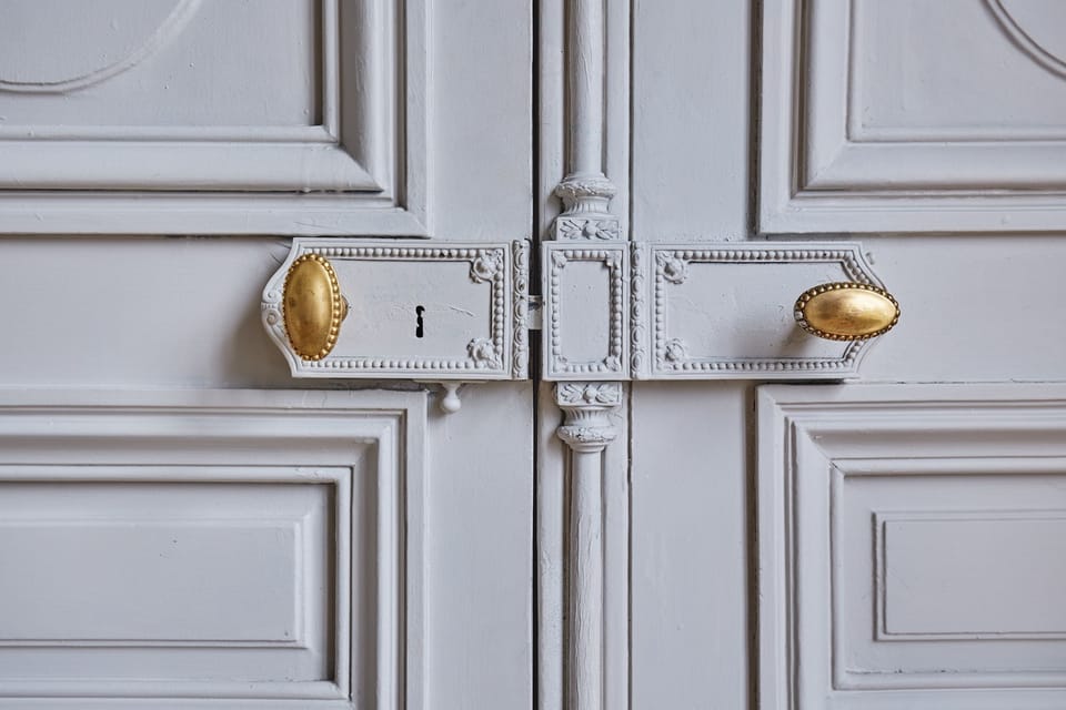 Classic French craftsmanship—ornate door detail with vintage brass handles.
