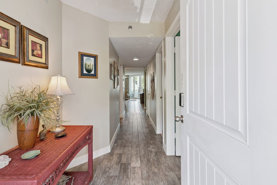 Step into this welcoming hallway with warm decor and art-filled walls. Wood-look floors guide you toward bright spaces and your relaxing retreat.