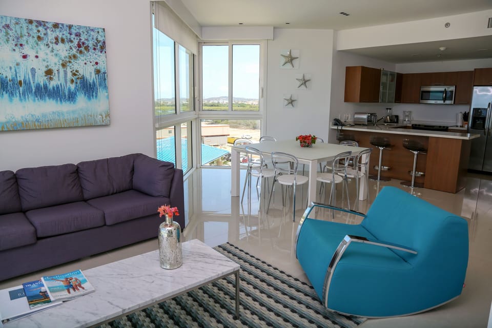 Relax in your bright, open-concept living space with sleek modern furnishings and stunning pool views through expansive windows. Starfish accents add a coastal touch to your home away from home.