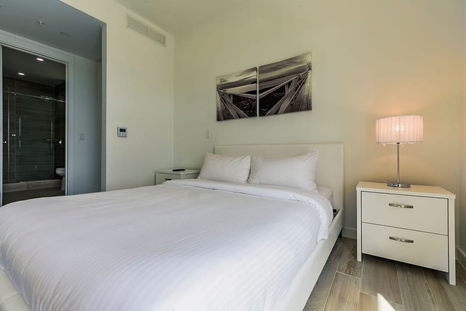 Sink into crisp white linens and unwind in your modern bedroom, complete with contemporary artwork and a sleek ensuite. Your perfect night's rest awaits.