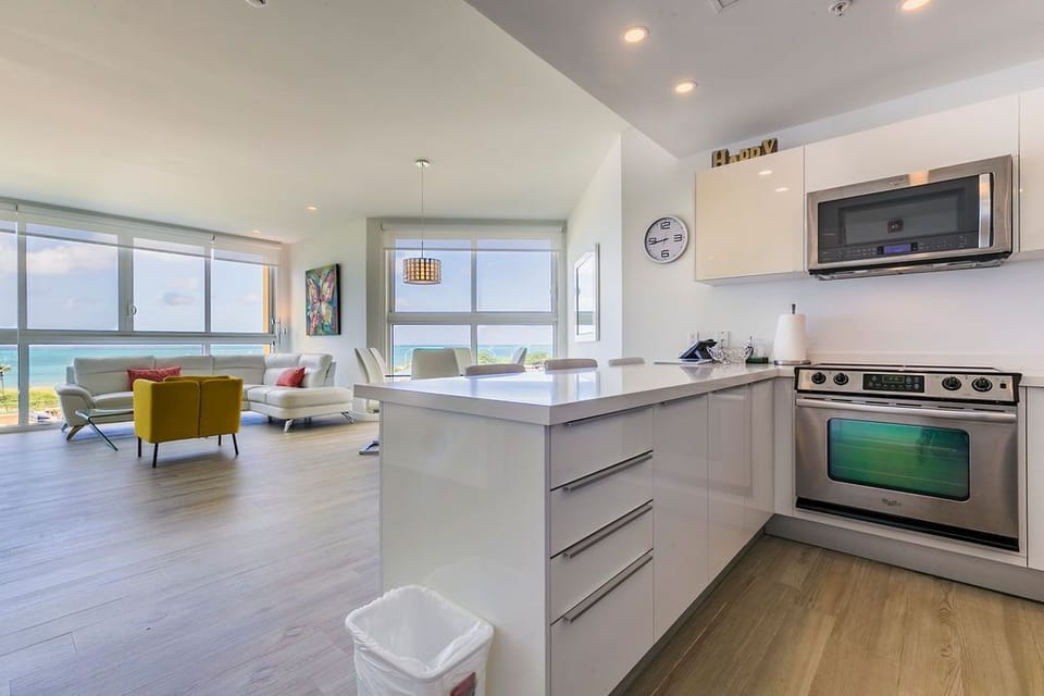 Your sleek, sun-filled retreat welcomes you with panoramic ocean views through floor-to-ceiling windows. Prepare meals in your modern kitchen while soaking in those turquoise blues, then relax in the airy living room where every moment feels like vacation.