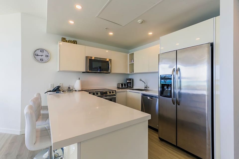 Your fully-equipped kitchen features stainless steel appliances, sleek countertops, and a breakfast bar—perfect for preparing meals or enjoying morning coffee in bright, modern comfort.