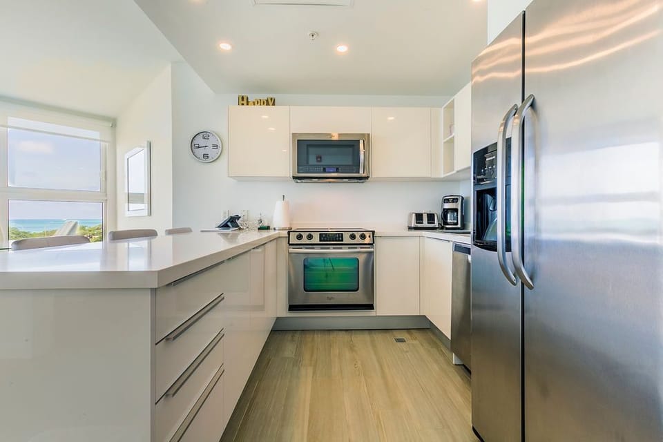 Your fully equipped kitchen features gleaming stainless steel appliances, sleek cabinetry, and a stunning ocean view through the window—perfect for preparing meals while soaking in coastal beauty.
