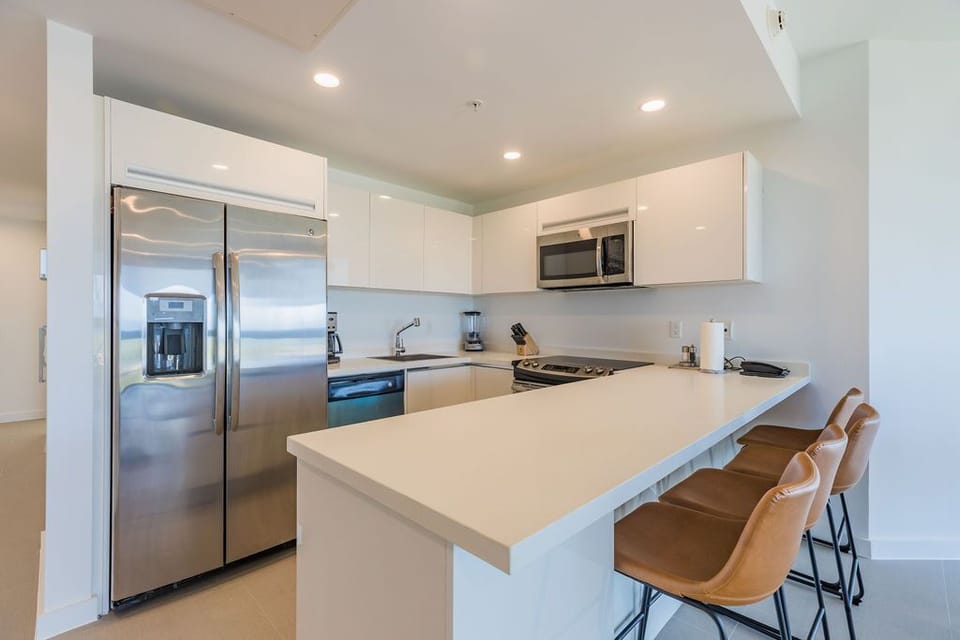 This sleek kitchen invites you to whip up anything from quick breakfasts to gourmet dinners. With stainless-steel appliances, modern white cabinetry, and a spacious island with seating, you'll find everything you need to feel right at home.