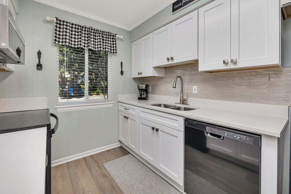 Ocean Walk M2 - Kitchen with white cabinets, tile backsplash, and black dishwasher