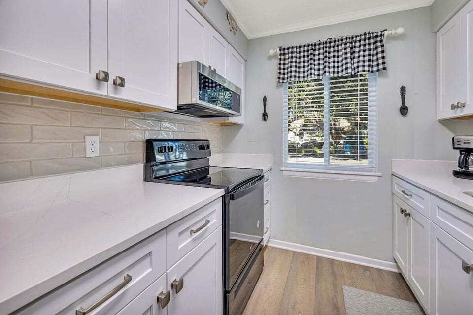 Ocean Walk M2 - Kitchen with white cabinets, stainless appliances, and tile backsplash