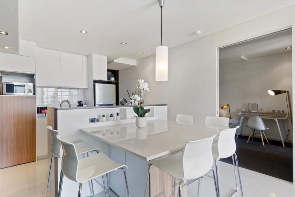 A bright, minimalist dining space framed by sleek white cabinetry and designer lighting – both functional and chic.