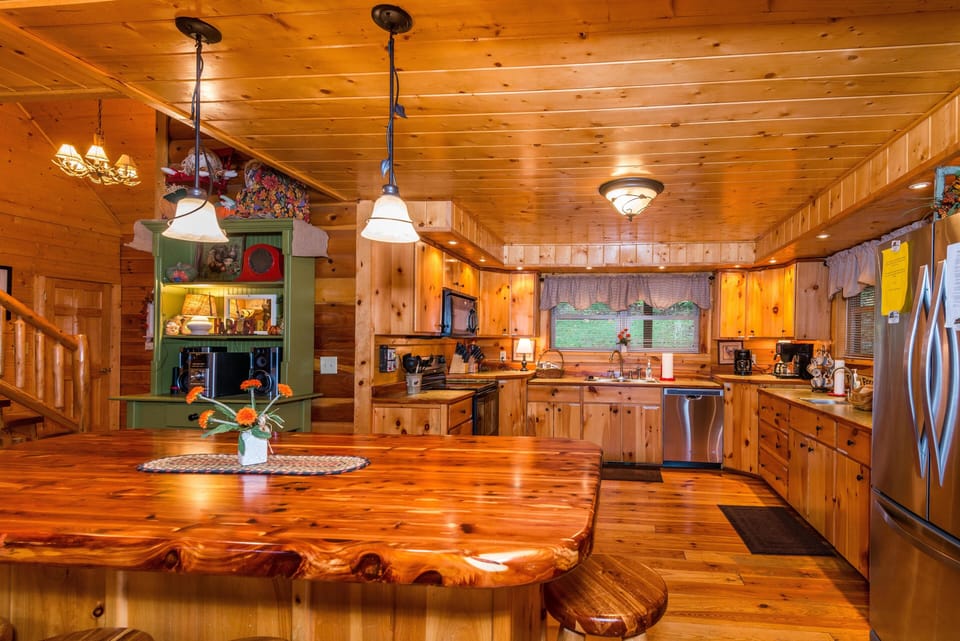 Polished wood island with matching stools lights the kitchen, featuring stainless steel appliances and pine cabinetry.
