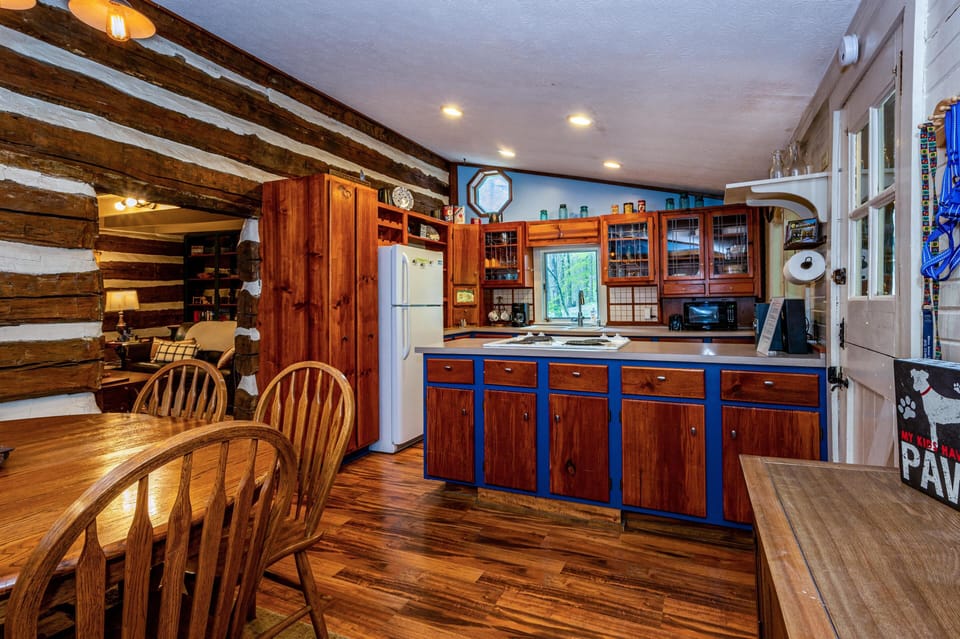 Cozy rustic kitchen with warm wood accents and an open dining area, perfect for gathering and shared meals.