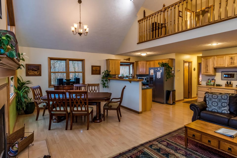 Open floor plan showing dining area with wood table and chairs beside kitchen with honey-toned cabinets and stainless appliances.