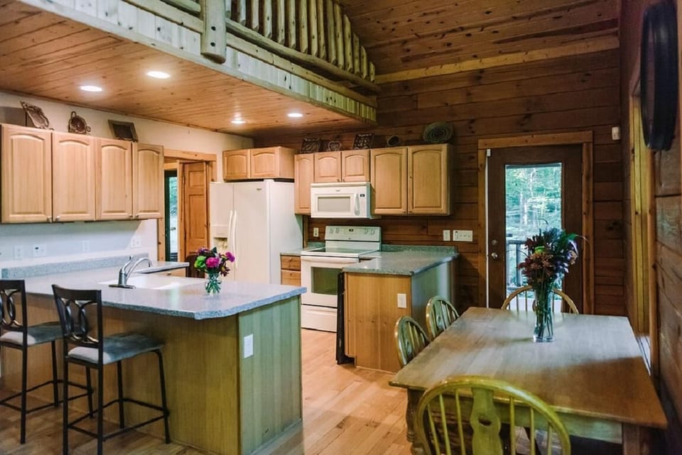 Kitchen and dining area feature light wood cabinetry, granite countertops, and a wooden table with four chairs.
