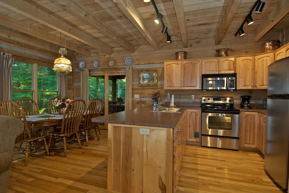 Wood-paneled kitchen and dining area with stainless steel appliances, a central island, and a large wooden table.