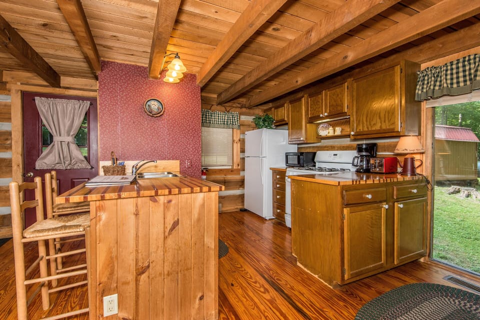 Kitchen with butcher block counters, oak cabinets, white appliances, and a door with a curtain.