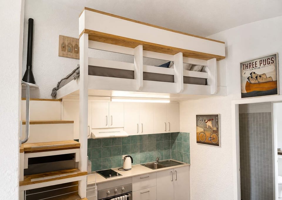 The timber staircase leads to the elevated loft sleeping space above the kitchen, adding character and a playful sense of adventure to the dome’s compact design.
