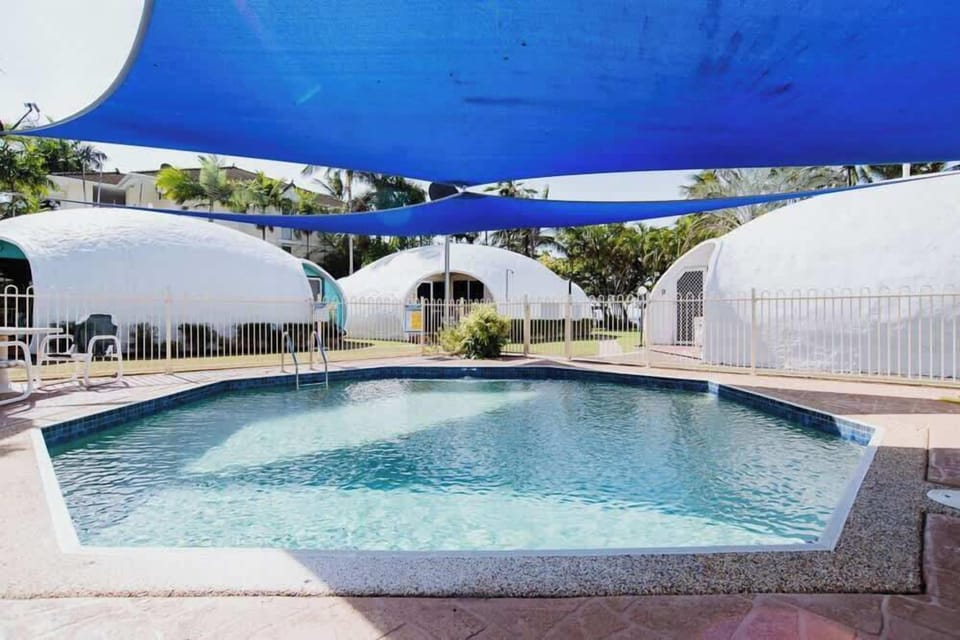 Cool off in the shared octagonal swimming pool, nestled amongst lush gardens and shaded seating areas.