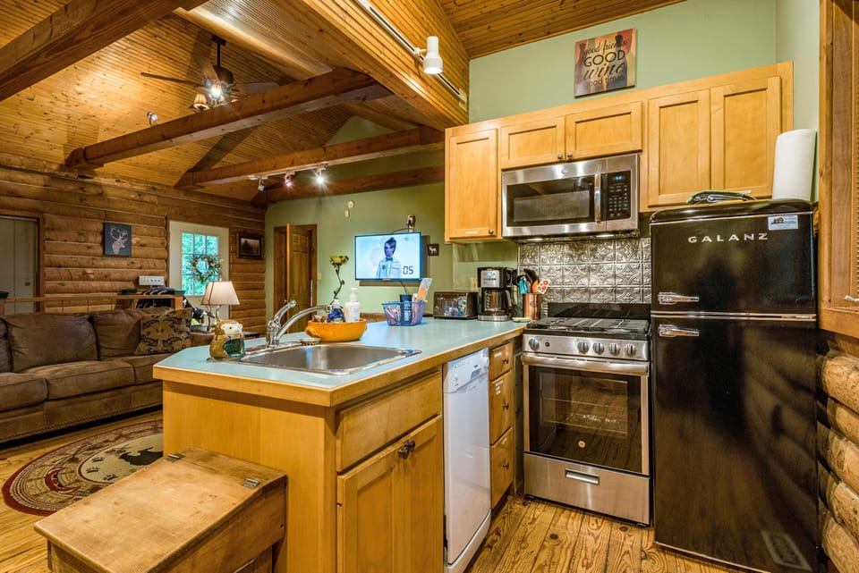 Kitchen area featuring light wood cabinetry, stainless steel appliances, and a log cabin interior