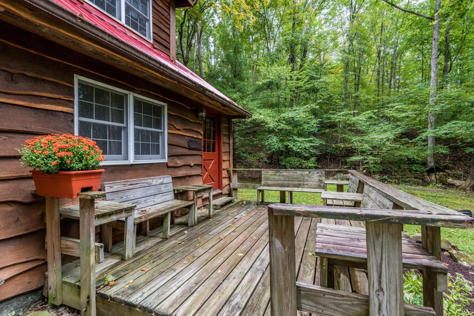Weathered wooden deck with built-in bench seating and orange flowers beside a brown wood exterior wall.