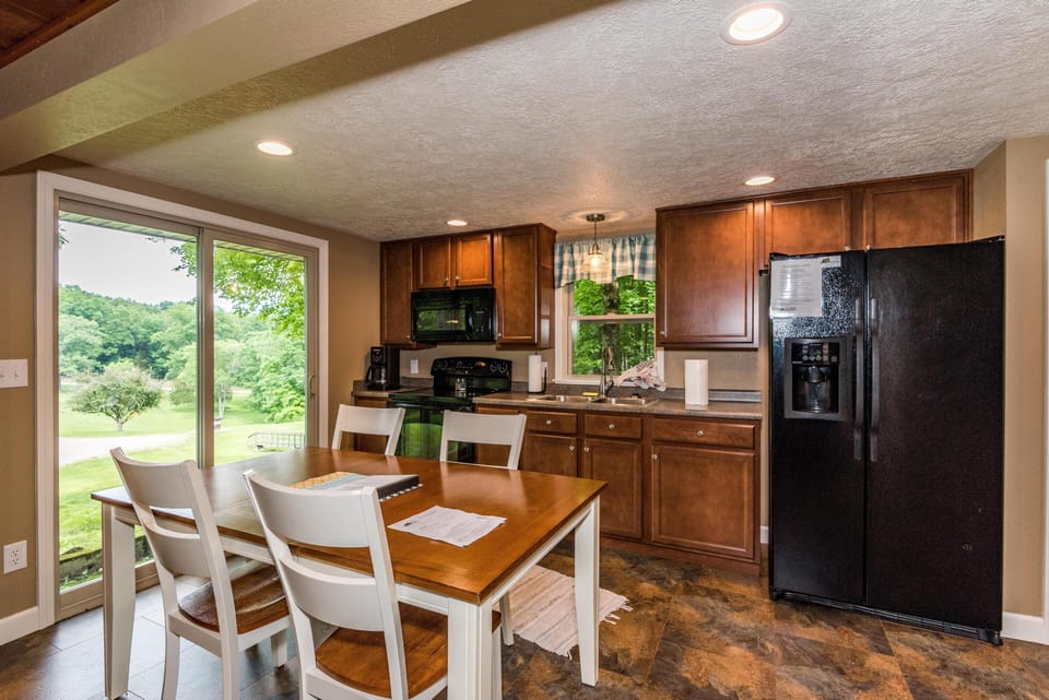 Kitchen and dining area with wood cabinetry, black appliances, and sliding glass doors overlooking green lawn.