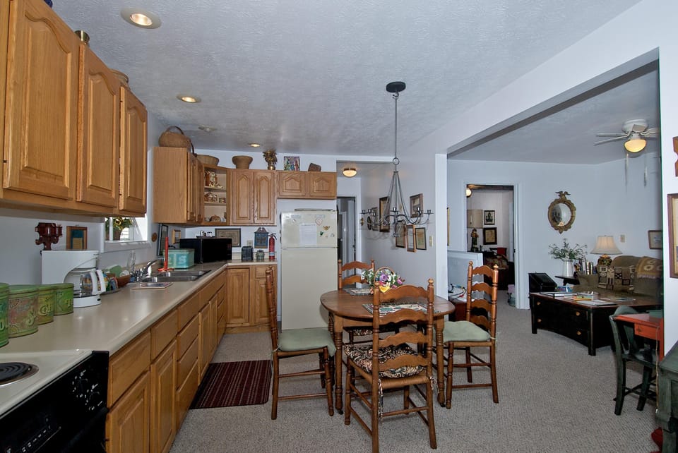 Kitchen and dining area with oak cabinetry, beige countertops, round wooden table, and vintage chandelier.