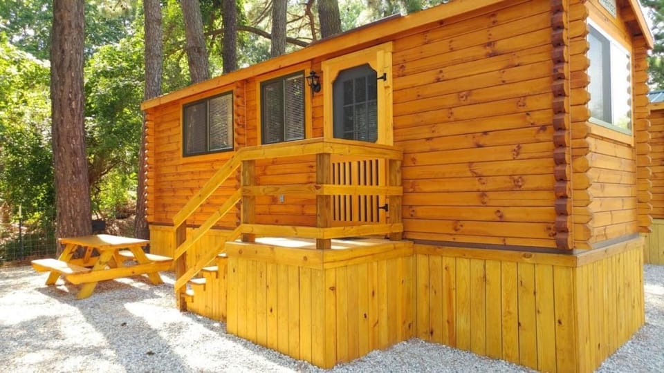 a wooden cabin with a bench and a porch at Anvil Campground in Williamsburg