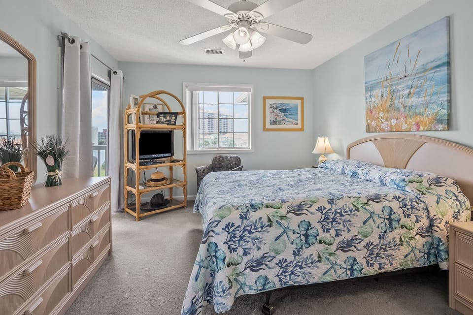 Bedroom with a wide window, ceiling fan and water views at Tilghman Shores B7, a 2-bedroom Cherry Grove condo