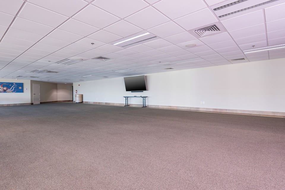 Spacious event room with a large TV, perfect for gatherings or meetings, offering a versatile space for your needs