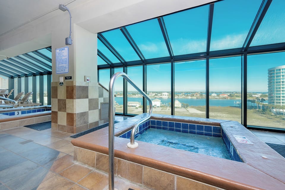 Relax in the hot tub while taking in stunning waterfront views from the indoor pool area at Phoenix IX in Orange Beach