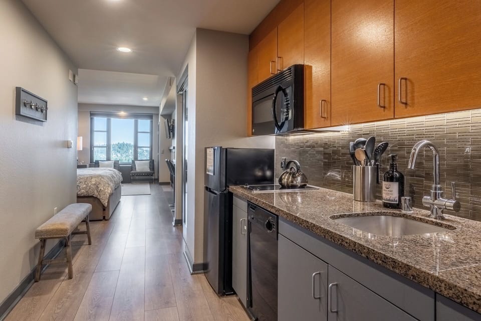 From the front door, the galley kitchen opens into the sleeping and living areas beyond, all warmed by natural light from the expansive windows.