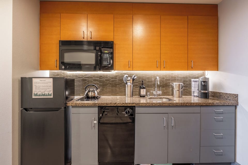 The galley kitchen includes an upgraded, larger refrigerator with a true freezer, along with a dishwasher, microwave, and two-burner cooktop—practical amenities that make everyday meals easier.