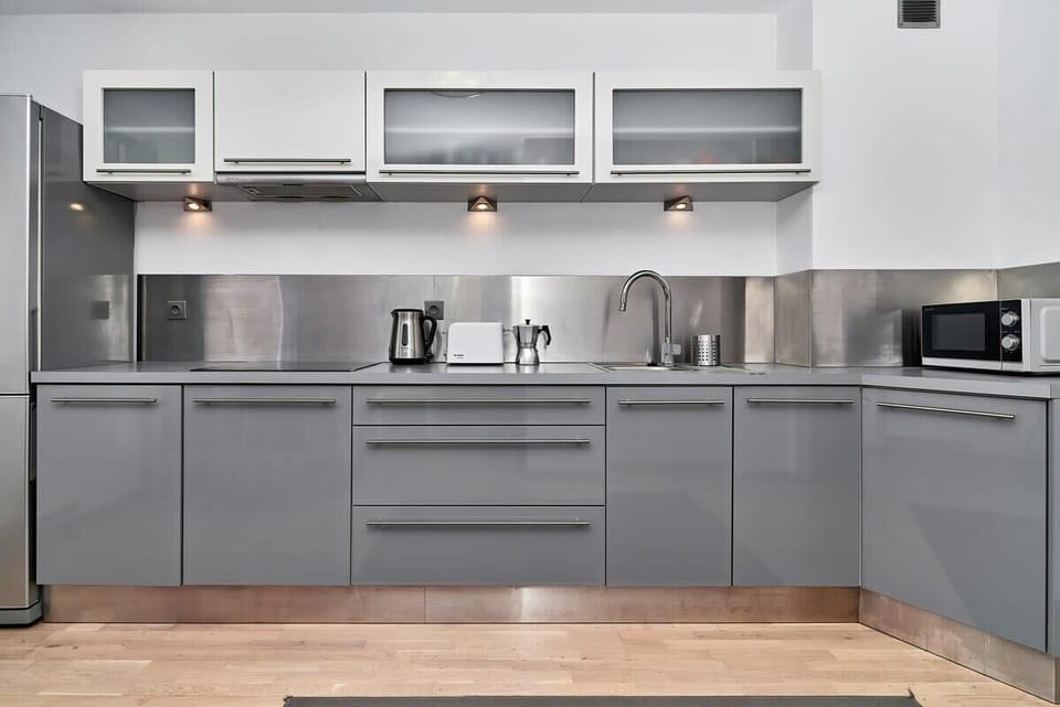 A closer look at the gray kitchen, emphasizing the cabinets and appliances. There's an entrance to the hallway in the background.
