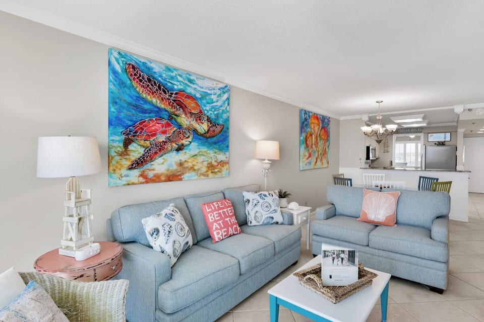Unwind on plush sofas beneath vibrant sea turtle art in your bright, coastal-themed living space with ocean-inspired decor and pillows.