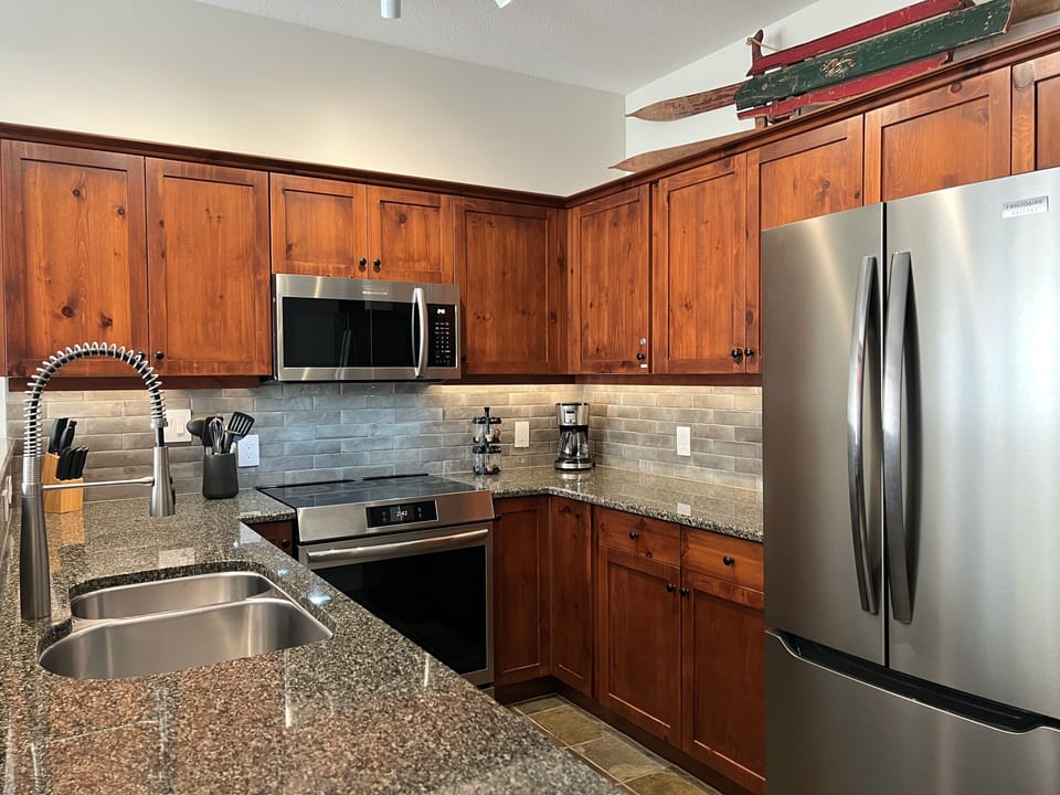 Kitchen with granite countertops, stainless steel appliances & custom backsplash