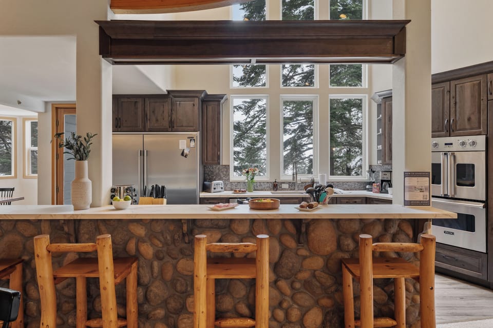 Rustic stone breakfast bar overlooking a bright, window-lined kitchen.