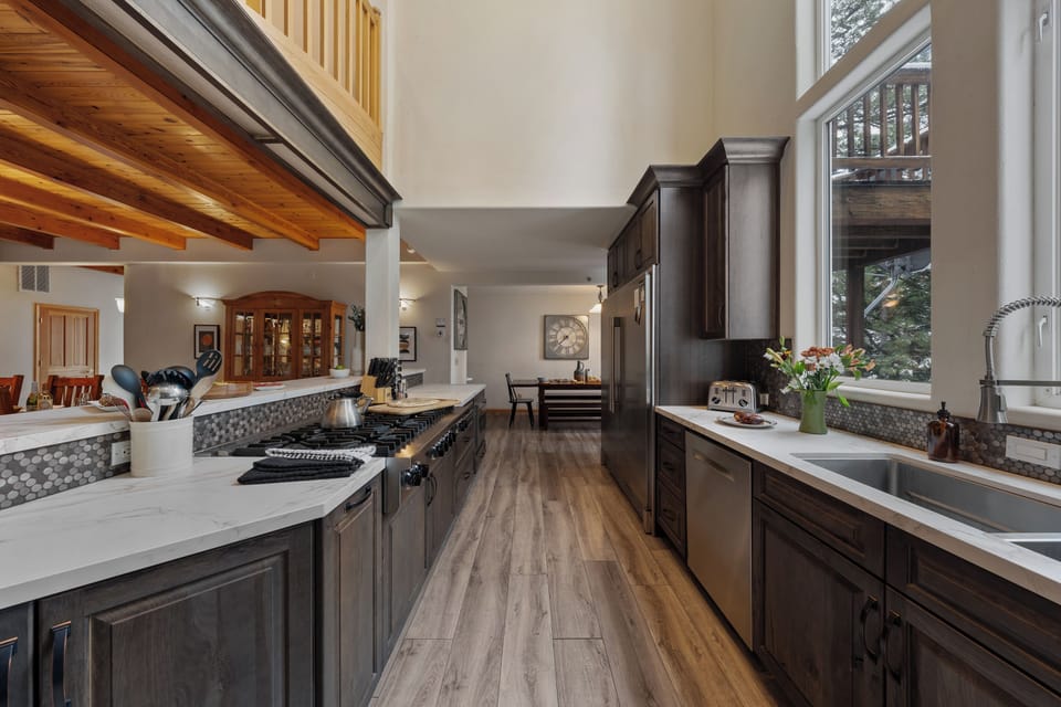 Chef-style kitchen with long prep counters, premium appliances, and woodland views.